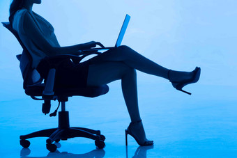 青年女士坐在椅子上使用平板电脑
