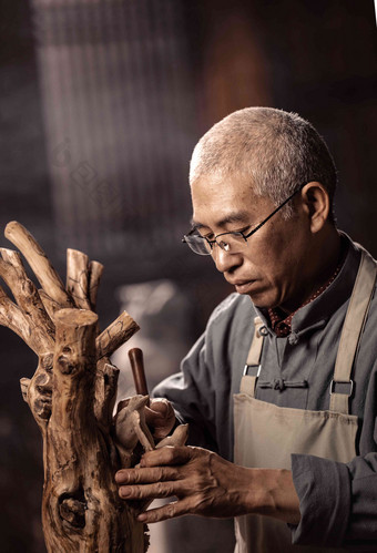 在树根上认真雕刻的工匠师木雕师高清图片