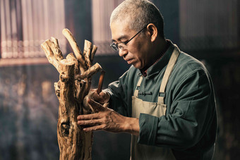 在树根上认真雕刻的工匠师东方高质量照片