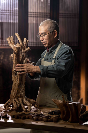 在树根上认真雕刻的工匠师中国清晰照片