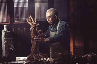在树根上认真雕刻的工匠师东亚写实图片