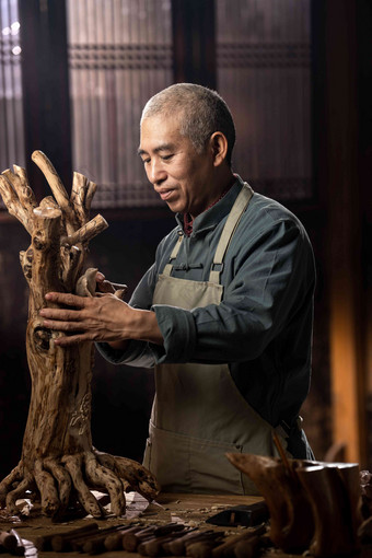 在树根上认真雕刻的工匠师东亚高端摄影
