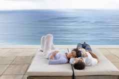 浪漫的年轻的夫妇放松日光浴浴床∞池度假胜地