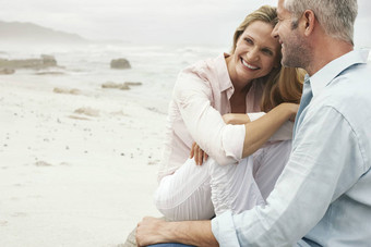 快乐爱的夫妇坐着海滩