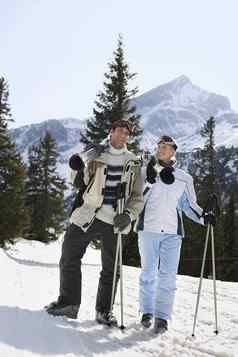 滑雪夫妇站携带滑雪板肩膀滑雪坡