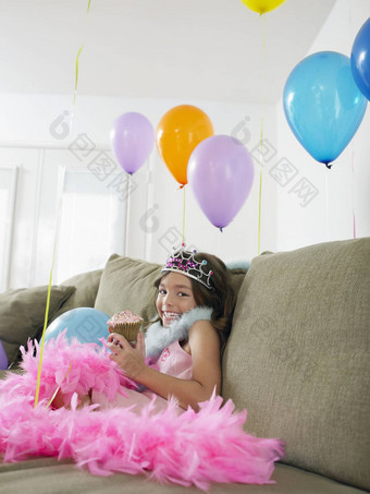 肖像快乐年轻的女孩坐着沙发气球蛋糕
