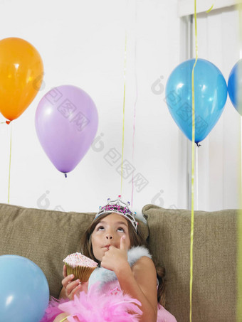 年轻的女孩坐着沙发气球蛋糕