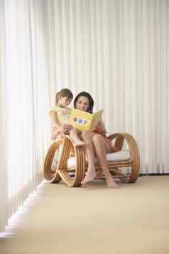 快乐妈妈。女儿阅读书扶手椅角落里房间