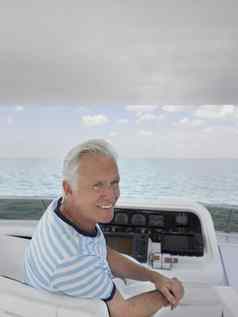 微笑中间岁的男人。坐着舵奢侈品游艇