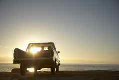 后视图年轻的夫妇拾音器卡车停前面海洋享受日落