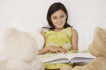 快乐女孩阅读故事书泰迪熊床上