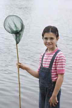肖像快乐年轻的女孩持有钓鱼网湖