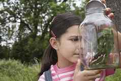好奇的女孩检查坚持昆虫Jar在户外