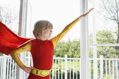 年轻的男孩超级英雄服装手臂扩展在室内