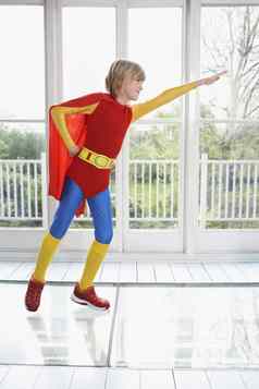完整的长度年轻的男孩超级英雄服装手臂扩展在室内
