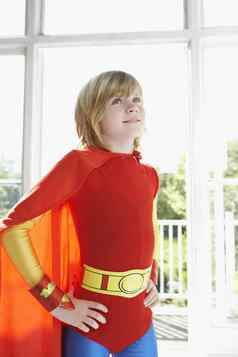 年轻的金发碧眼的男孩超级英雄服装站手臀部在室内
