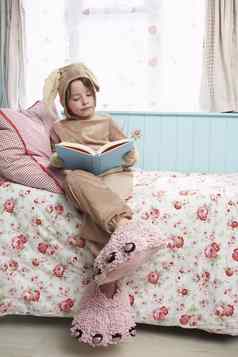 年轻的女孩兔子服装怪物拖鞋阅读书床上