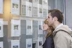 一边视图年轻的夫妇窗口显示真正的房地产办公室