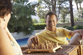 快乐夫妇玩国际象棋游泳池