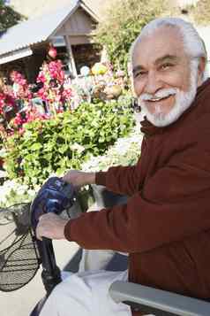 肖像快乐高级男人。电动机踏板车植物花园