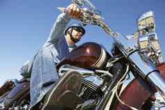低角视图年轻的男人。骑摩托车清晰的天空