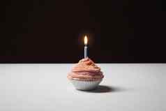 粉红色的蛋糕点燃生日蜡烛表格孤立的黑色的背景
