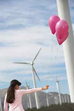 年轻的女孩玩粉红色的气球涡轮机风农场