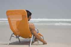 男人。坐着帆布躺椅海滩考虑