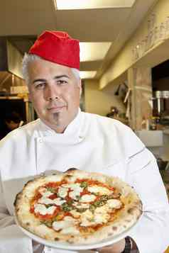 肖像自信老板穿首饰持有披萨商业厨房