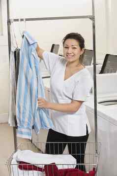 肖像快乐年轻的女人挂衬衫前面洗机器自助洗衣店