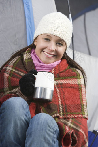 肖像快乐年轻的女包装毯子持有咖啡杯