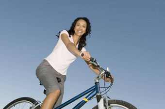 女人坐在山自行车清晰的蓝色的天空