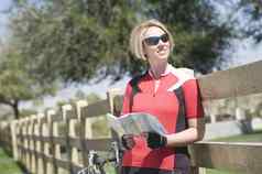 女骑自行车持有路线图倾斜栅栏公园