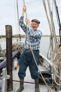 上了年纪的渔夫拉绳子甲板