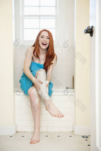 肖像年轻的女人浴室应用奶油腿