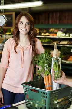 快乐年轻的女人手持有蔬菜超市