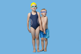 快乐年轻的男孩女孩泳装持有手蓝色的背景
