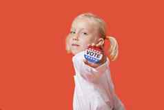 肖像年轻的女孩显示投票徽章粉红色的背景