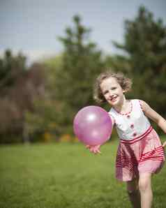 年轻的女孩玩紫色的球公园