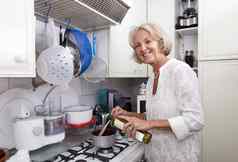 肖像高级女人添加橄榄石油平底锅厨房计数器