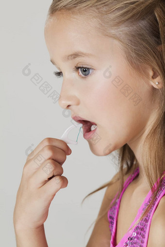 年轻的女孩用<strong>牙线</strong>清洁牙齿牙齿灰色的背景