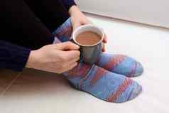 女人持有热喝穿温暖的针织袜子