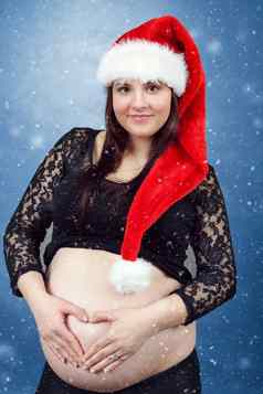 美丽的怀孕了圣诞老人女人温柔持有肚子