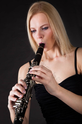 美丽的年轻的女人玩<strong>单簧管</strong>