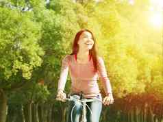 漂亮的亚洲年轻的女人骑自行车公园