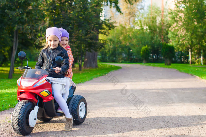 可爱的女孩骑儿童摩托车绿色公园