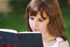 文学年轻的美丽的女孩阅读书户外