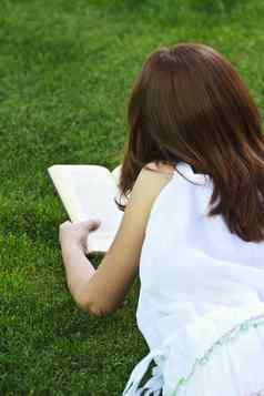 女学生年轻的美丽的女孩阅读书户外