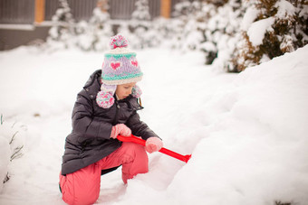 可爱的女孩玩雪铲冬天一天