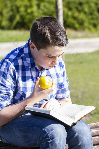 幸福年轻的男人。阅读书户外黄色的苹果